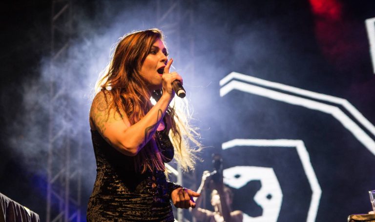 Pitty se apresenta em palco com luz iluminando por trás