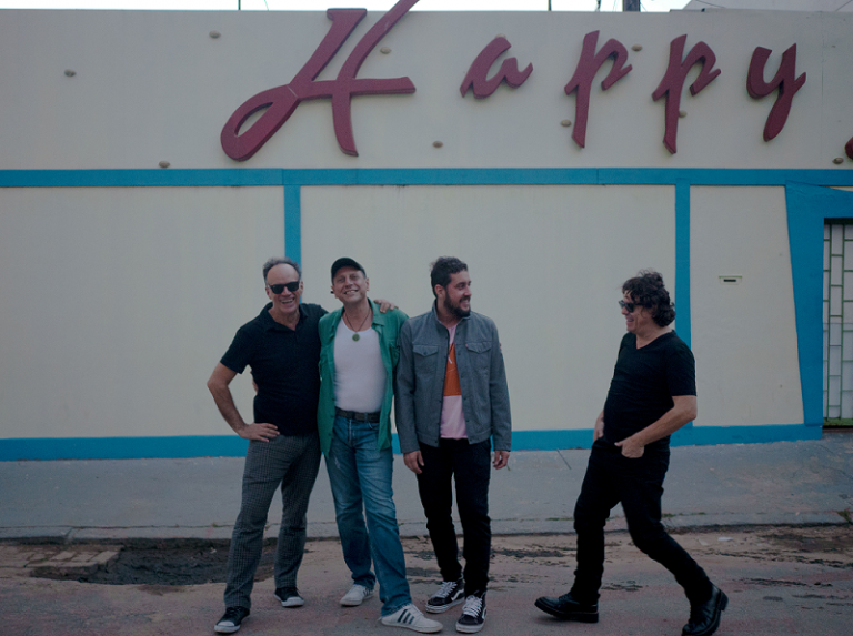 banda barão vermelho posa para foto em frente a parede escrito "happy"