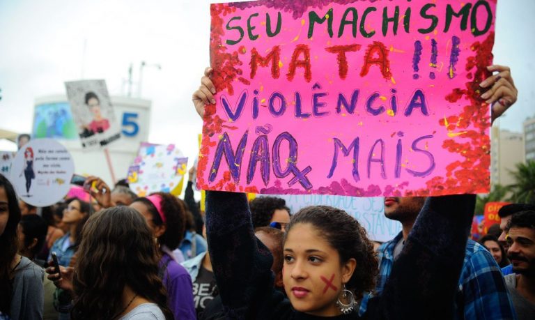 Menina segura uma faixa com dizeres contra o feminicidio